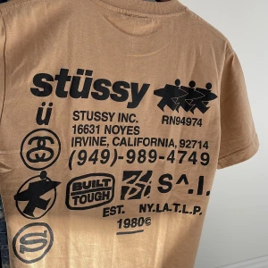 Beige t-shirt från Stüssy - Säljer en beige t-shirt från Stüssy med tryck på både fram- och baksida. T-shirten har en klassisk rund hals och korta ärmar. Perfekt för en avslappnad stil.