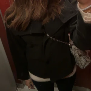 Svart kappa - Snygg svart kappa med knappar framtill. Perfekt för kyligare dagar och ger en stilren look. Passar bra till både jeans och klänning. 