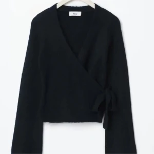 Svart omlottkofta från gina - Snygg svart omlottkofta från gina med knytning i sidan. Använd rätt sällan så bra skick men lite nopprig. Wrap koftan 