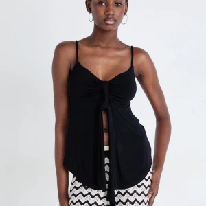 Svart ärmlös topp med knyt - Snygg svart ärmlös topp med knyt framtill. Gina topp med smala axelband och en luftig passform. Passar bra till både jeans och kjol. Kontakta gärna mig för frågor💓💓 använt 2 ggr 