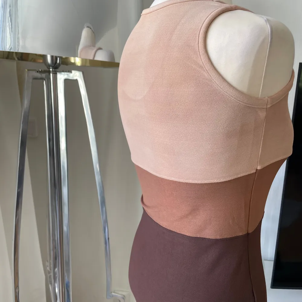 Snygg ärmlös klänning i flera nyanser av brunt och beige. Klänningen har en tight passform och är gjord i ett mjukt, stretchigt material. Perfekt för en stilren look. Alla lappar är bortklippta . Mekot.