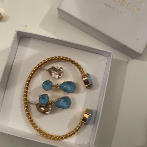 Smyckeset från Caroline Svedbom - Pris kan diskuteras! (armband limited edition 750kr, blå öronhängen  300kr st, armband + öronhängen 1000kr o allt tillsammans 1150krElegant smyckeset från Caroline Svedbom med guldpläterade detaljer och blå stenar, Perfekt för att lägga till en färgklick till din outfit. De finns även ett par öronhänhen me vita stenar som också är från Caroline svedbom allt är oanvänt då jag fått de i present o de faller inte mig i smaken. Man kan köpa allt enskilt eller allt i ett 