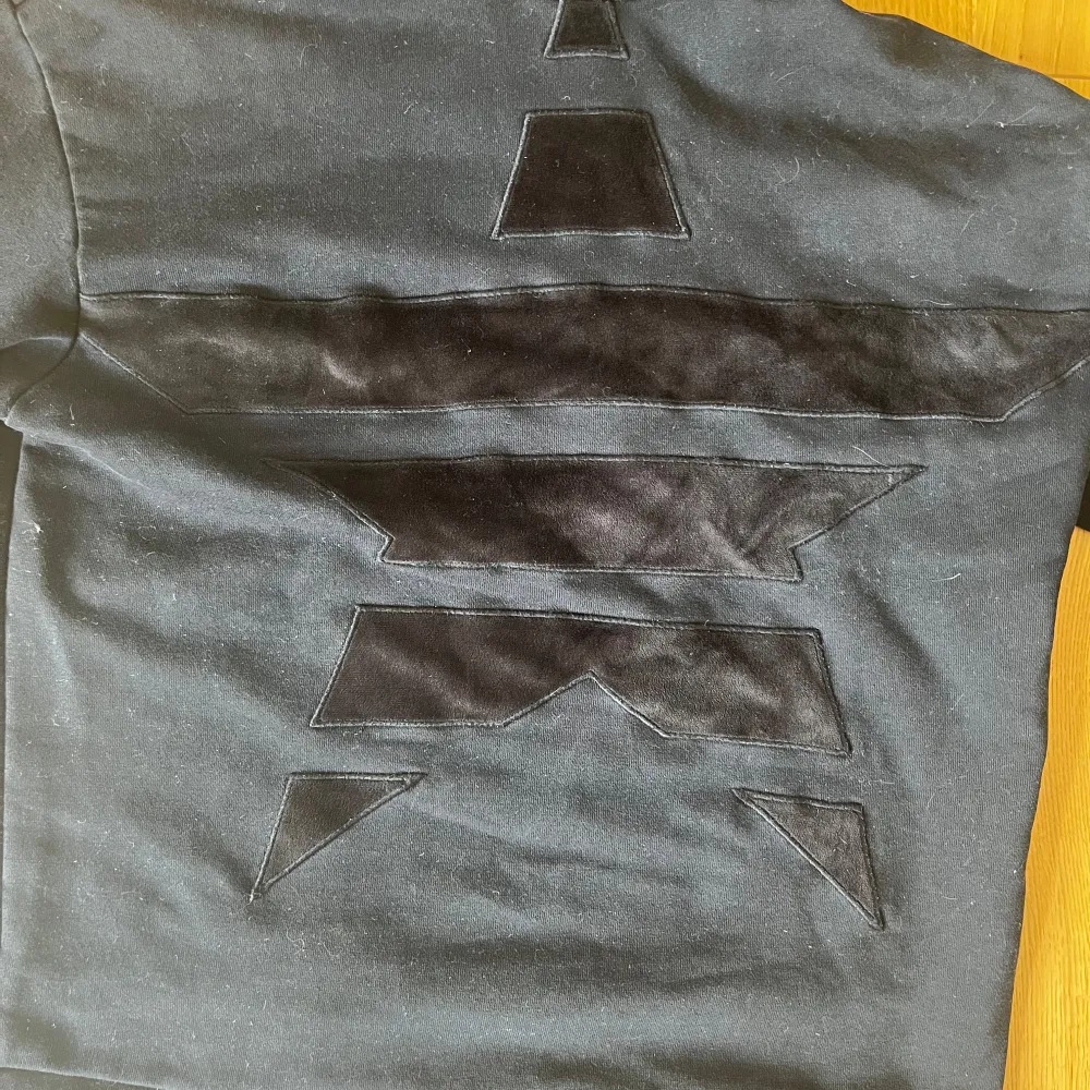 Snygg svart hoodie från Emporio Armani med ett unikt geometriskt mönster på framsidan. Tröjan har en klassisk huva och långa ärmar, perfekt för en stilren look. Den är tillverkad i ett mjukt material som ger en bekväm passform.. Hupparit & Collegepaidat.