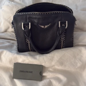 Svart skinnväska från Zadig & Voltaire - Säljer min Sunny XS studs bag ifrån Zadig & Voltaire eftersom den inte används längre. Den köptes våren 2023 för 4500. Finns knappt några tecken på användning förutom att vissa av studsen har tappat lite färg när man kollar noga. (Dustbag medföljer)