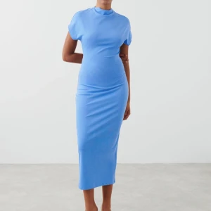 Blå tight klänning med öppen rygg - Snygg blå klänning med korta ärmar och en elegant öppen rygg med knytning. Klänningen har en tight passform och når ner till vaderna, vilket ger en stilren och modern look. Använd ett tillfälle