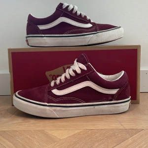 Vans Old Skool i vinröd och vit - Snygga Vans Old Skool sneakers i vinröd mocka med vita detaljer och snörning. Perfekta för en avslappnad stil med klassisk design och bekväm passform.