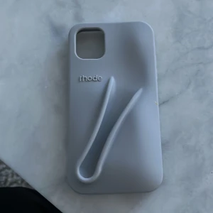 Grå mobilskal från Rhode - Snyggt och stilrent grått mobilskal från Rhode. Skalet har en unik design med en upphöjd detalj på baksidan 