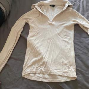 Säljer en stilren beige ribbad tröja från Amisu. Tröjan har en v-ringad design och långa ärmar, perfekt för en avslappnad look. Tillverkad i ett mjukt och bekvämt material.
