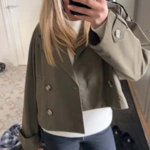 Olivgrön kappa - Säljer en olivgrön kappa/trench coat med dubbelknäppning och stora knappar. Jackan är i xxs men är mer som en s/m och långa ärmar med uppvikta muddar. Skriv för fler bilder. Och buda gärna 