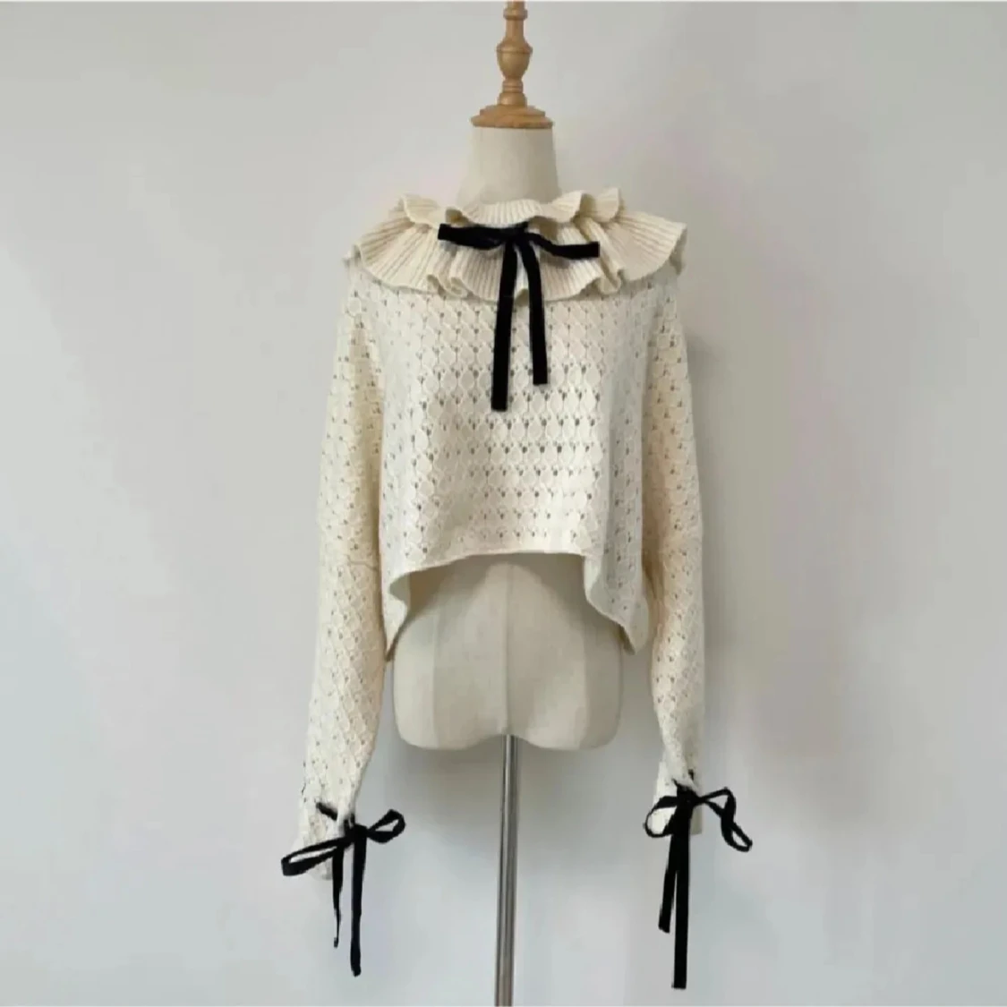 Vit stickad tröja med volangkrage och rosetter