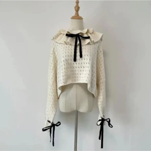 Vit stickad tröja med volangkrage och rosetter - Supersöt vit stickad tröja med volangkrage och svarta rosetter vid halsen och ärmsluten. Storlek S. Nyskick. Kom gärna med prisförslag