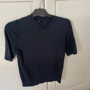 Mörkblå stickad kortärmad tröja - En stilren mörkblå stickad tröja med korta ärmar och rund halsringning. 