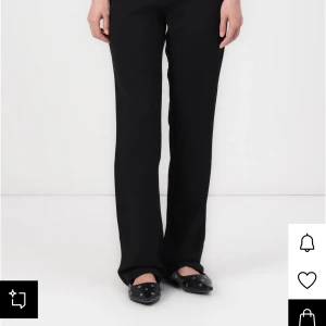 Svarta kostymbyxor med bootcut - Svarta kostymbyxor med hög midja och bootcut-snitt. Byxorna har en klassisk rak passform med lätt utsvängda ben och bälteshällor i midjan. Perfekta för en clean och stilren look, säljer dessa pga att dem inte passar, testade en gång med lappen kvar! Storlek XXLx32 men skulle säga att den mer passar som en M! 