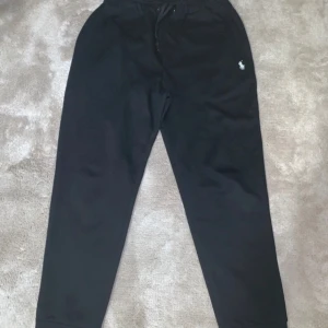 Svarta mjukisbyxor Polo Ralph Lauren - Svarta mjukisbyxor från Polo Ralph Lauren med dragsko i midjan och klassisk logga broderad på låret. Sköna och stilrena, perfekta för chill eller träning. Tillverkade i mjukt bomullsmaterial för extra komfort.