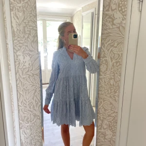 Ljusblå broderad klänning med v-ringning - Superfin ljusblå klänning med broderade detaljer och v-ringning. Klänningen har lång ärm och en luftig passform med volang nertill. Perfekt för vår och sommar, och student mottagningar till exempel💞original pris 889kr