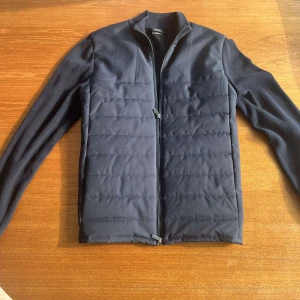 Svart quiltad jacka från Massimo Dutti - Stilren svart jacka från Massimo Dutti med quiltad framsida och släta ärmar. Jackan har hel dragkedja och är tillverkad i exklusiv bomull. Perfekt för dig som gillar en clean look med lite edge.