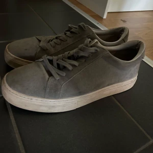 Gråa vagabond skor i mocka - Stilrena grå sneakers i mocka med klassisk rund tå och platt vit sula. Skorna har snörning och en enkel, clean design som passar till det mesta. Perfekta för dig som gillar en minimalistisk look.