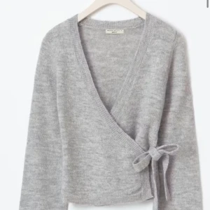  Gina Tricot knitted wrap cardigan - Supermjuk grå omlottkofta från Gina Tricot med knyt i sidan och v-ringad hals.  knitted wrap cardigan koftan är använd 1 gågn säljer den då den inte har kommit till användning för mig. Den är slut såld i butik och online  