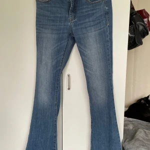 Blå bootcut jeans från Madlady - Snygga blå bootcut jeans från Madlady i klassisk denim med lätt slitning. Modellen har mid midja och vida ben nertill.