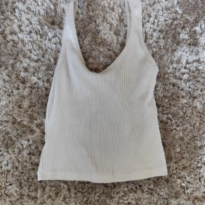 Ribbad beige linnetopp Stradivarius XS - Superenkel och snygg ribbad linnetopp från Stradivarius i beige. Modellen är ärmlös med breda axelband och djup rundad ringning. Perfekt att matcha med jeans eller kjol för en chill look.