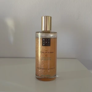 Rituals The Ritual of Karma body oil - Glowig kroppsolja från Rituals, The Ritual of Karma. Oljan har en skimrande guldig finish och kommer i en genomskinlig glasflaska med guldfärgat lock. Perfekt för att ge huden en snygg lyster och doft.