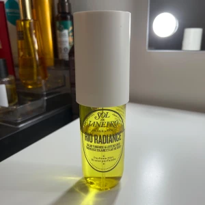 Sol de Janeiro Rio Radiance parfym - Fräsch och tropisk parfymmist från Sol de Janeiro, Rio Radiance. Flaskan är genomskinlig med gul vätska och har en vit, rund kork. Doften har inslag av solig tuberos och kokosmjölk. Perfekt för dig som älskar somriga och exotiska dofter.