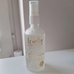 Loelle Neroli Water Face Mist 100ml - Fräsch ansiktsmist från Loelle med ekologiskt nerolivatten. Kommer i en frostad glasflaska med vit spraypump och guldiga detaljer. Perfekt för att återfukta och pigga upp huden under dagen. Innehåller 100 ml och passar alla hudtyper.