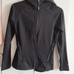 Svart hoodie jacka/ kofta med dragkedja - Svart hoodiejacka med hel dragkedja framtill och två snedställda fickor med dragedjor. Kan hämtas upp i Malmö. 