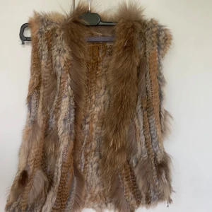 Brun pälsväst i äkta päls - Säljer en  lyxig pälsväst. Västen är gjord av 60% kaninpäls och 40% murmeldjurspäls, vilket ger en cool och unik look. Storlek S/ M skulle jag säga 