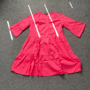 Rosa volangklänning från Esmara - Snygg rosa klänning från Esmara med volanger och trekvartsärmar. Modellen är luftig och har en avslappnad passform, perfekt för varma dagar. Tillverkad i mjuk bomull som känns skön mot huden. Enkel men trendig design som sticker ut med sin starka färg.