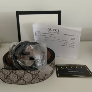 GG Supreme beige bälte - Snyggt bälte i beige med klassiskt GG Supreme-mönster och svart GG-spänne. Bältet är gjort i canvas med skinn-detaljer och har en stilren, lyxig vibe. Perfekt accessoar för att lyfta din outfi.