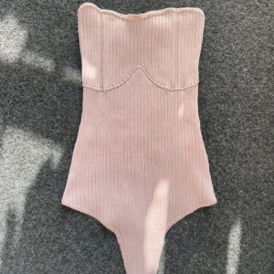 Ribbad rosa -tubbody Missguided - Supersnygg ribbad tubbody från Missguided i ljusrosa. Toppen är axelbandslös och har en bandeauformad överdel med markerade sömmar framtill. 
