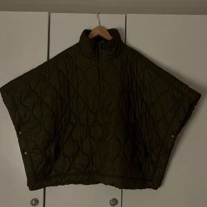 Quiltad mörkgrön väst  - Säljer en oversized quiltad dunväst i mörkgrönt med hög krage och half zip framtill. Västen har bred passform, tryckknappar i sidorna och två snedställda fickor. Perfekt för lager-på-lager.💞
