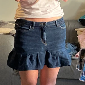 Mörkblå jeanskjol med volang - Supersnygg mörkblå jeanskjol med volangkant nertill. Perfekt för dig som vill ha en cool och trendig look med lite extra edge. Jag har sytt den själv, men allt är noggrant gjort💕 skulle säga att den är s-m i storleken, har ett par till liknade kjolar i fler färger till salu just nu och fler kommer upp inom kort💖