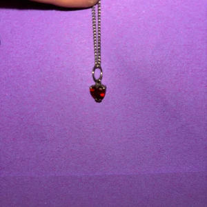 Halsband med röd hjärtberlock - Sött halsband med tunn silverfärgad kedja och en liten hjärtformad berlock i rött. Perfekt accessoar för att ge din outfit en romantisk touch. Hjärtat har en glansig finish och kedjan är diskret men stilren.