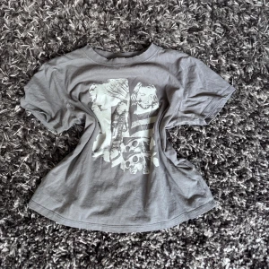 Grå t-shirt med tryck - Säljer en grå t-shirt från H&M med ett stort tryck framtill i vitt. Klassisk passform med rund hals och korta ärmar. Perfekt för dig som gillar en cool och avslappnad stil.
