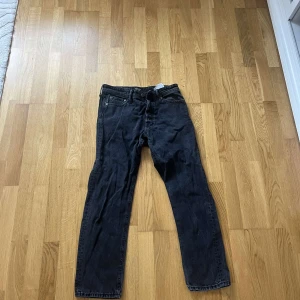 Jack & Jones jeans 30/30 - Säljer ett par svarta jeans i klassisk rak modell. Jeansen har fem fickor, knapp- och dragkedjegylf samt snygga kopparfärgade nitar. Perfekta till en avslappnad streetstil eller till vardags. Materialet är slitstarkt denim.