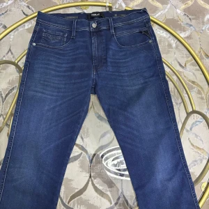 Blå Replay Hyperflex jeans straight fit - Säljer ett par blå Replay Hyperflex jeans med klassisk femficksdesign och raka ben. Jeansen har snygga slitningar framtill, normal passform och är tillverkade i stretchigt denim för extra komfort. Perfekta för dig som gillar stilrena och bekväma jeans. Nypris 1400kr