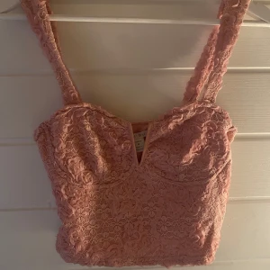 Rosa spetsig croppad festtopp - Säljer en superfin rosa croppad linnetopp från NewYorker med v-ringning och spetsdetaljer. Toppen har breda axelband och är täckt av blommig spets, perfekt för att lyfta vilken outfit som helst. Aldrig använd💞
