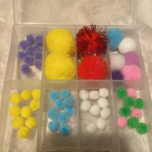 Färgglada dekorationsbollar i olika storlekar - Säljer ett set med fluffiga dekorationsbollar i olika färger och storlekar. Innehåller bland annat röda glitterbollar, gula, blå, vita, lila, rosa och gröna bollar. Perfekt för pyssel och dekoration. 11 st små lila bollar, 9 st små gula bollar, 10 st små blåa bollar, 11 st små vita bollar, 3 st små rosa bollar, 6 st små gröna bollar. Lådan som är i bilden kommer inte med i köpet 
