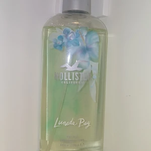 Hollister Lunada Bay Body Mist - Fräsch body mist från Hollister i doften Lunada Bay. Flaskan är transparent med gröna och blå nyanser samt blommotiv på framsidan. Perfekt för dig som gillar lätta och blommiga dofter.