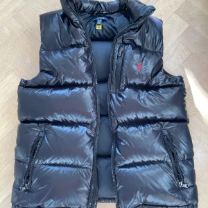 Polo ralph lauren väst svart - Säljer en svart dunväst från Polo Ralph Lauren, inte använd så mycket och är mycket fint skick. Storleken är en xl men passar mig perfekt och jag har vanligtvis medium i storlek