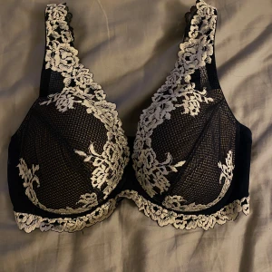 Svart spets-bh med blommigt mönster - Säljer en mörklbå intimissimi bh med vacker vit spets och blommigt mönster. Bh:n har breda axelband och fina spetsdetaljer längs kanterna. Perfekt för dig som vill ha något både snyggt och bekvämt. I nyskick då den knappt är använd, köpt förra sommaren. Storlek 75D 🫶
