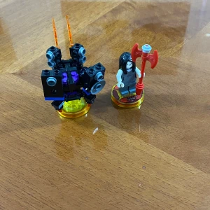 LEGO Dimensions figur och fordon - Säljer en LEGO Dimensions figur med långt svart hår, vit tröja och röd yxa samt tillhörande svart och lila fordon med orangea detaljer. Båda står på genomskinliga gula basplattor. Perfekt till samlingen eller spelet. Fungerar perfekt i spel.