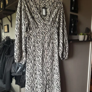 Zebramönstrad långklänning med knappar - Säljer den populära adoore dopen från lager 157 som är slutsåld, långklänning med zebramönster i svart och vitt. Klänningen har v-ringning, långa ärmar och knappar framtill. 