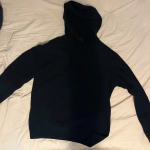 Svart hoodie från Oscar Jacobson - Säljer en stilren mörkblå hoodie från Oscar Jacobson. Tröjan har huva och långa ärmar, perfekt för en avslappnad och snygg look. Tillverkad i mjukt material och passar bra till jeans eller andra byxor.