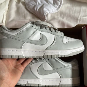 Nike Dunk Low retro - Säljer ett par Nike Dunk Low i en clean ljusgrå och vit färgkombination. Skorna är helt nya och oanvända! Kvitto finns! Bara att höra av sig vid frågor ☀️