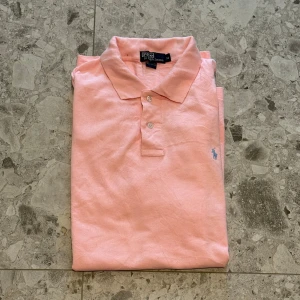 Ljusrosa pikétröja från Polo Ralph Lauren - Säljer en klassisk ljusrosa pikétröja från Polo Ralph Lauren i  bomull. Väldigt stor i sin storlek så tror den hade passat L/XL. Nypris cirka 1500kr