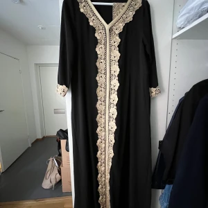 Svart Klänning med gulddetaljer - Säljer en svart klänning perfekt till förlovning eller annat. Den är endast använd en gång. Den är i storlek M, och det är inga defekter på den. Medföljer även ett matchande skärp! Pris kan diskuteras!!!🥰