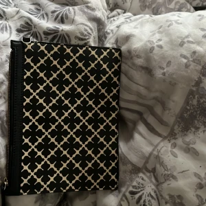 Svart och beige mönstrad kuvertväska från By Malene Birger - Säljer en snygg kuvertväska från By Malene Birger i svart och beige med klassiskt grafiskt mönster. Väskan har dragkedja upptill och är perfekt för att bära det viktigaste. Den är lite smutsig inuti där av priset 